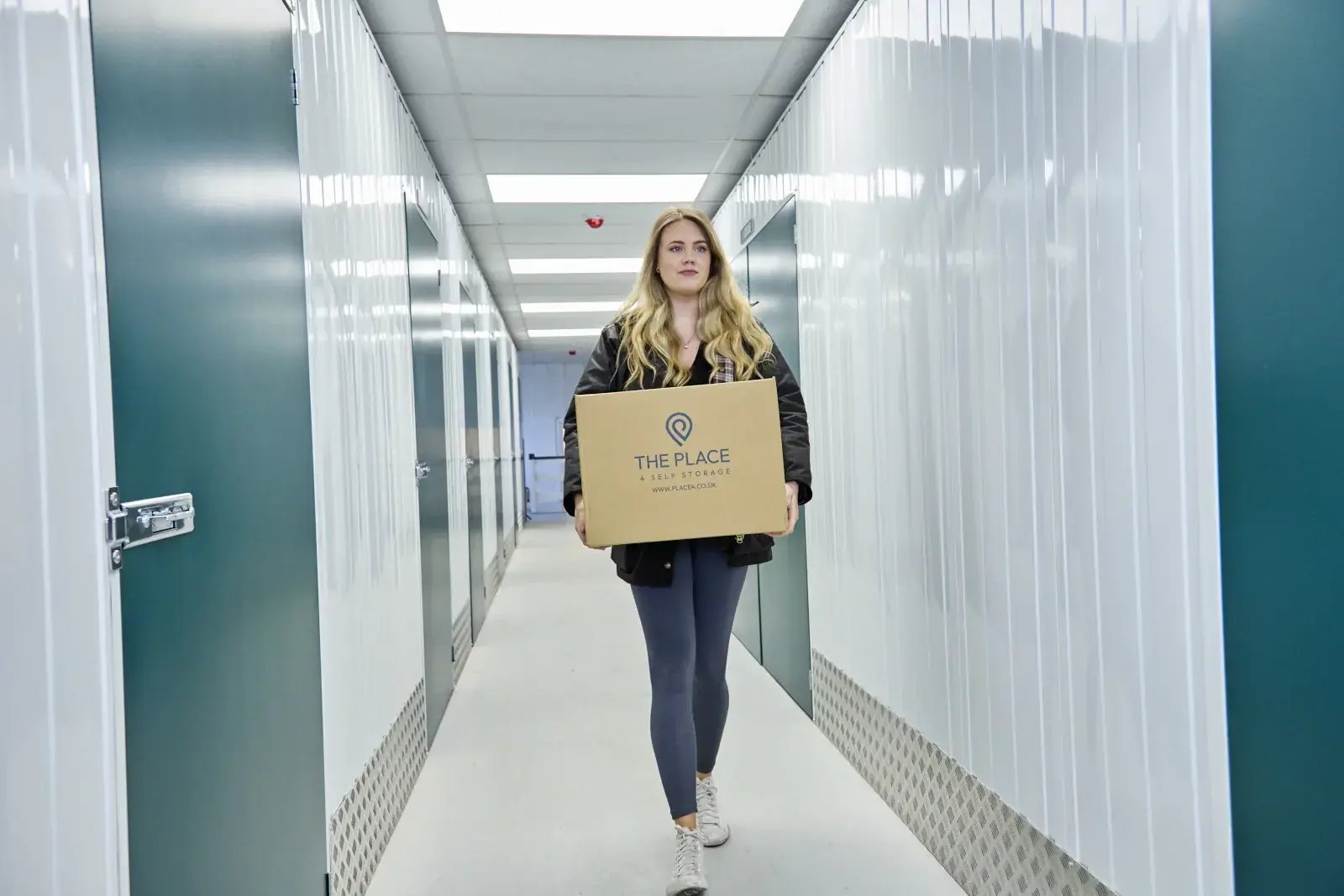 the-place-4-self-storage-customer-walking-down-corridor-taking-box-to-secure-lock-up-unit-1600x1067