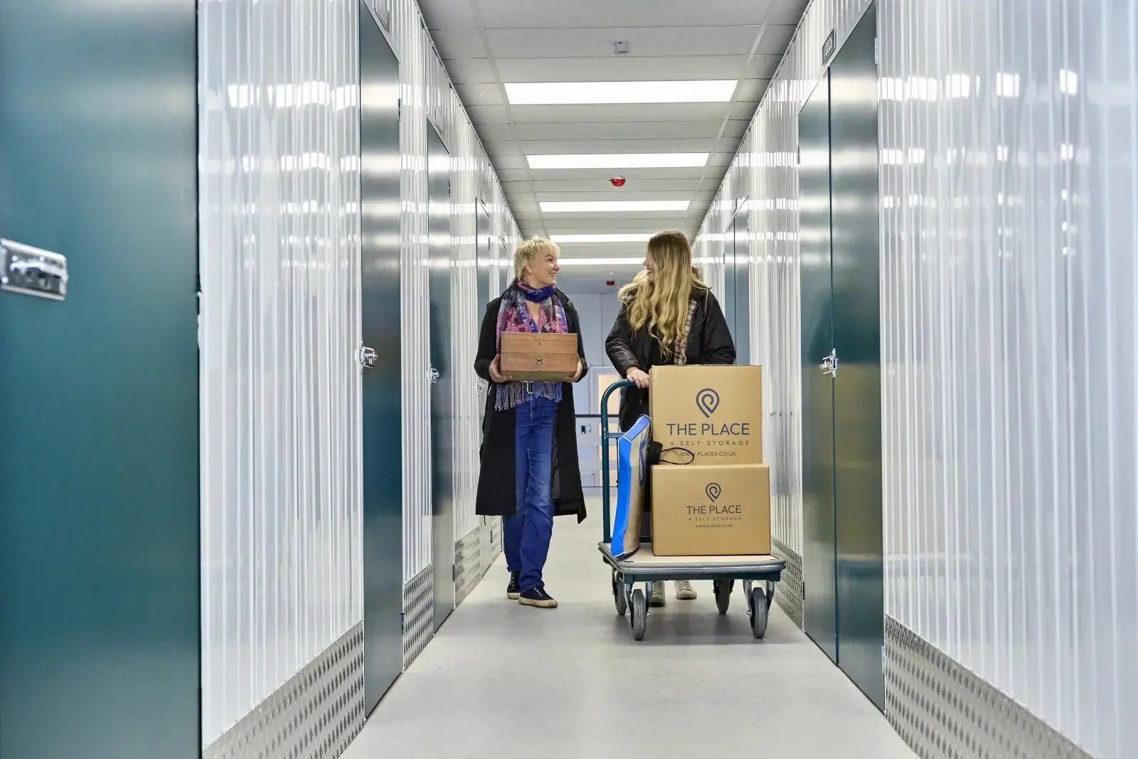 the-place-4-self-storage-customers-with-loaded-trolley-and-carrying-personal-items-to-storage-unit-1600x1067