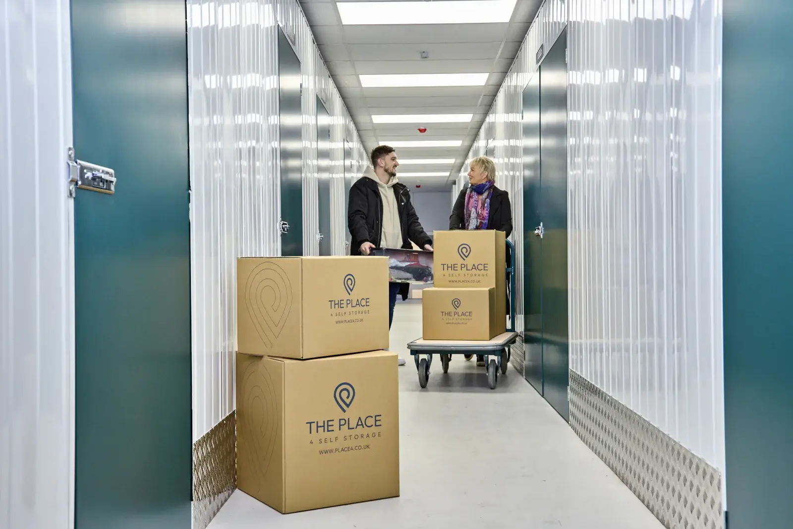 the-place-4-self-storage-customers-moving-packed-boxes-to-secure-personal-storage-unit-1600x1067