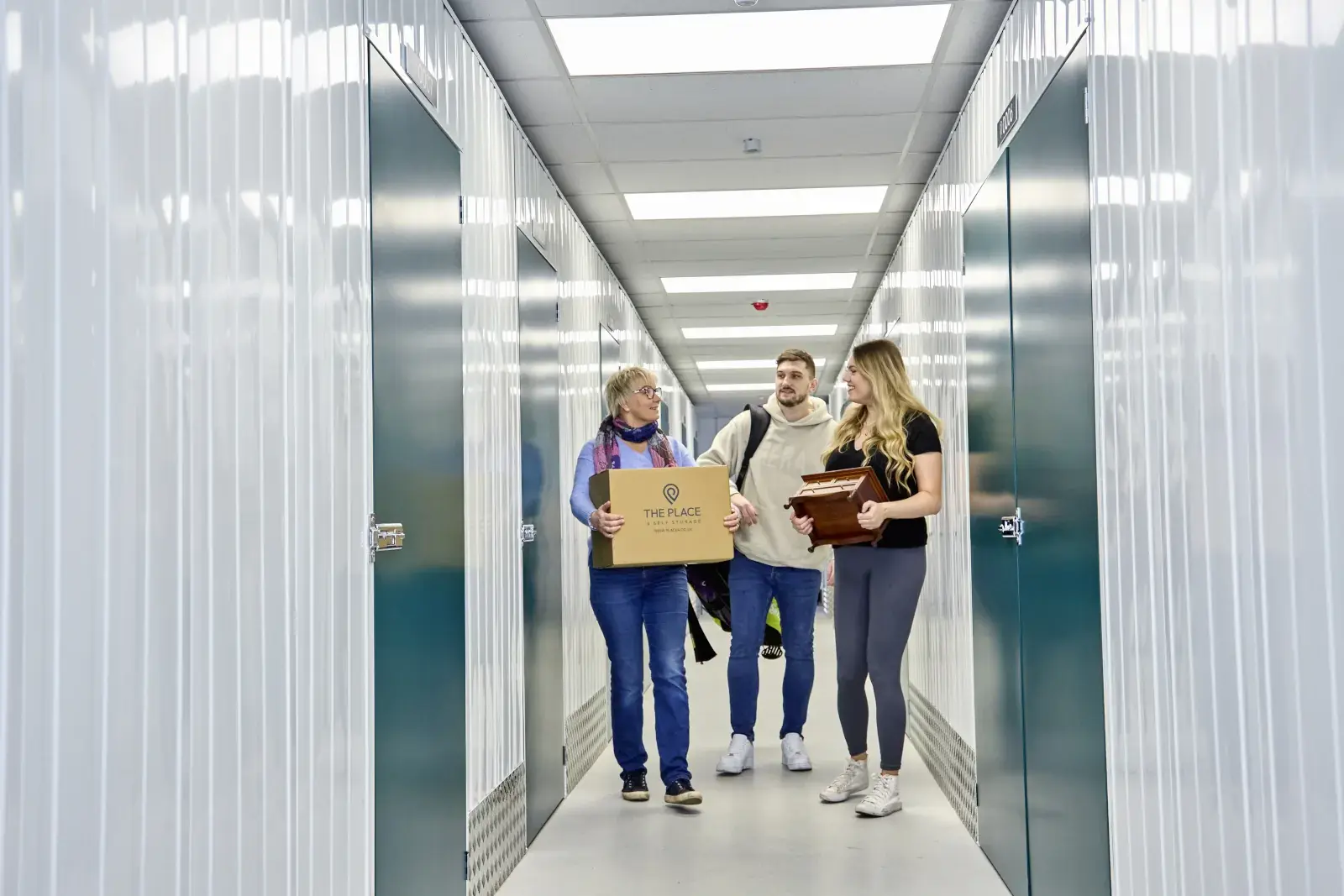 the-place-4-self-storage-family-carry-possessions-to-hired-secure-lock-up-unit-1600x1067